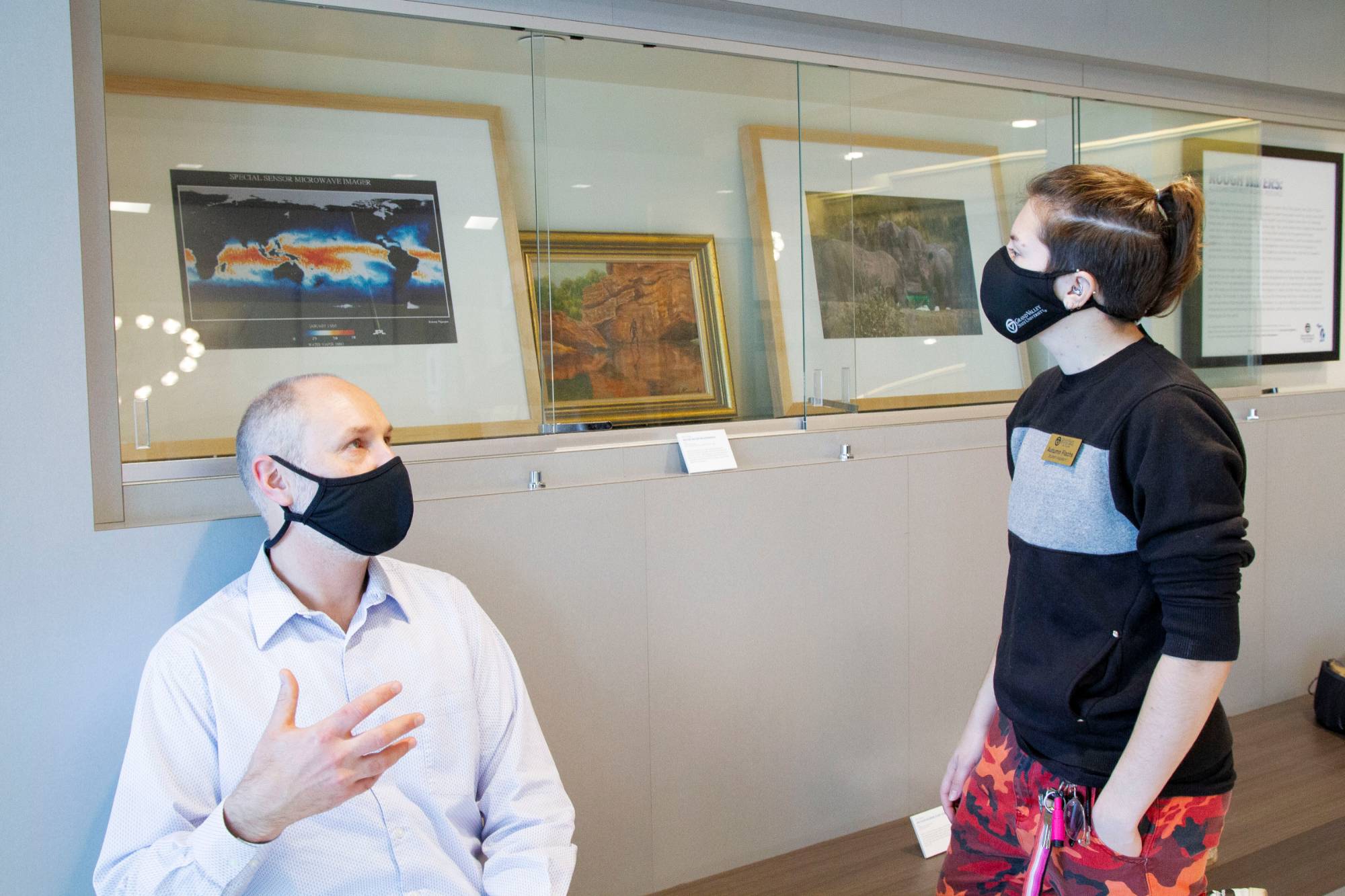 GVSU student and Art Gallery employee, Autumn Flachs, talked with Exhibitions Curator, Joel Zwart in front of their exhibition titled Rough Waters.